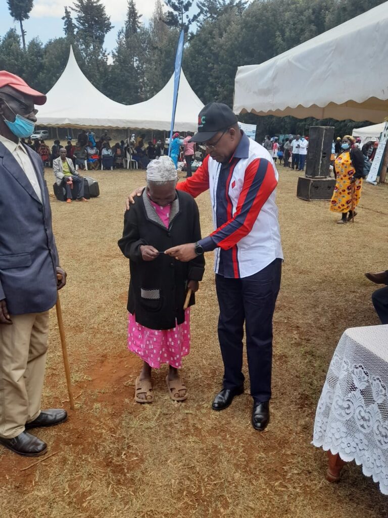 Othaya MP Gichuki Mugambi issuing NHIF card to one of the beneficiaries