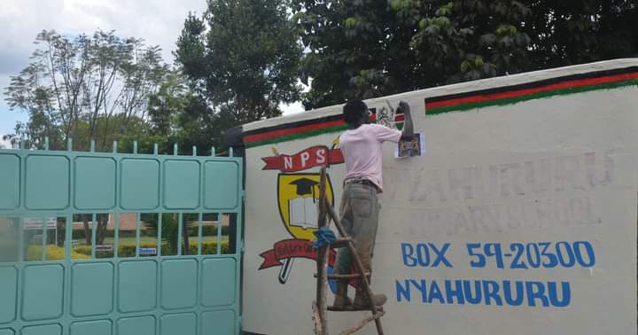 A painter working on a school's gate ahead of opening next week