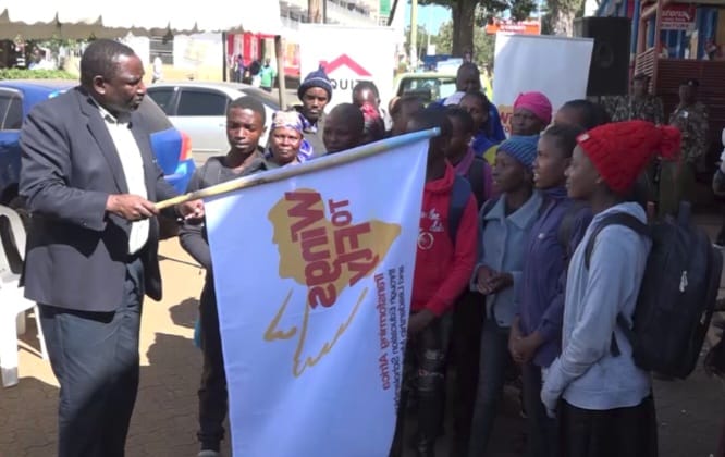 Kirinyaga Central SubCounty Director of Education Kennedy Machora flagging off Equity's Wings to Fly beneficiaries