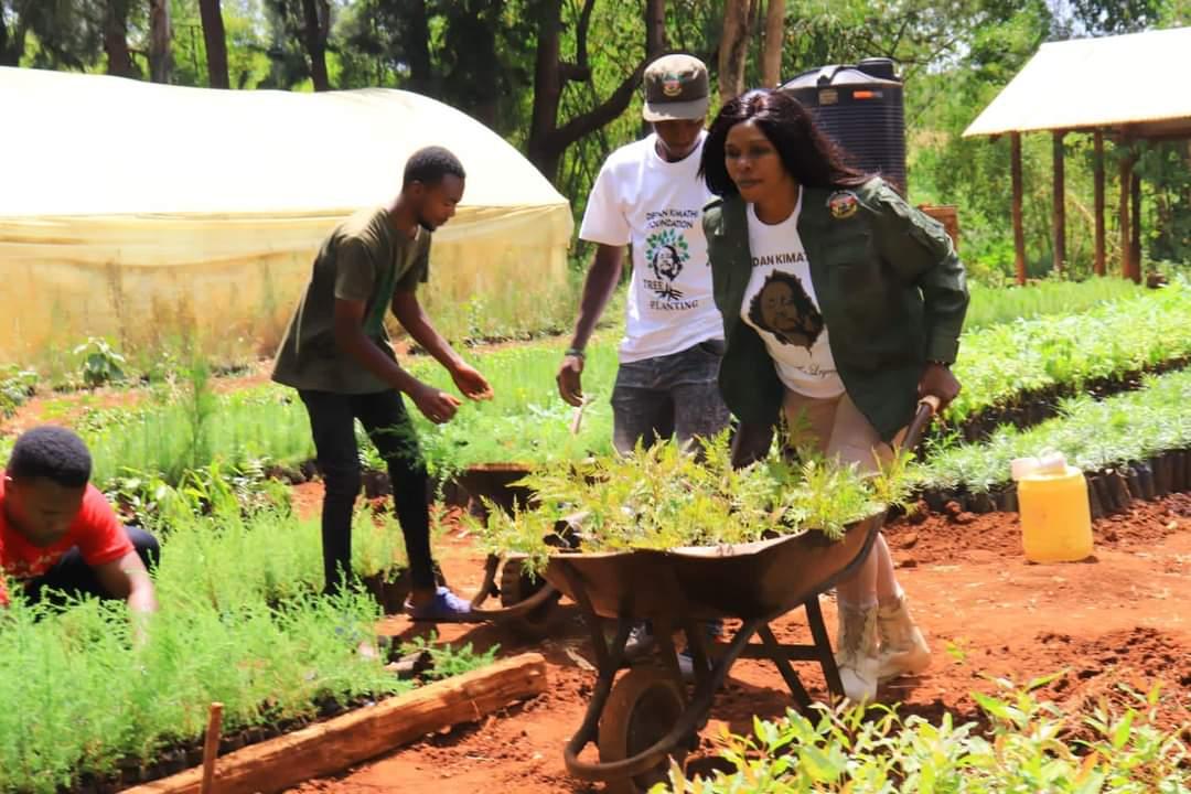 Dedan Kimathi Foundation Chief Executive Officer Evelyn Kimathi with wheelbarrow carrying trees