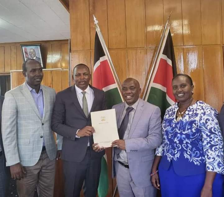 Water and Sanitation PS Dr Paul Rono handing over an MOU to Samburu County Governor Lati Leleltit as area Senator and Women Representative looks on