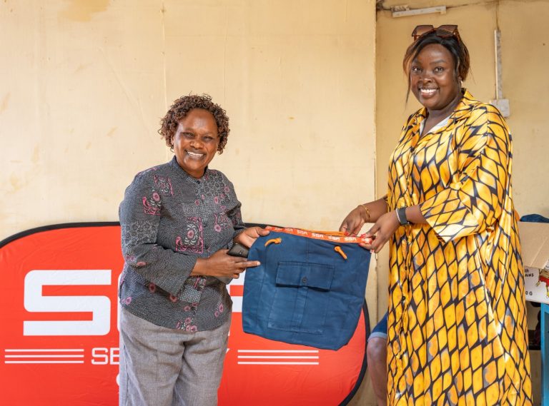 SGA Security Group PR and Branding Manager Josephine Wanjiru hands over a bag to Ms Fransisca Kiio during a visit to Wings of Hope Rescue Home to celebrate International Women's Day.