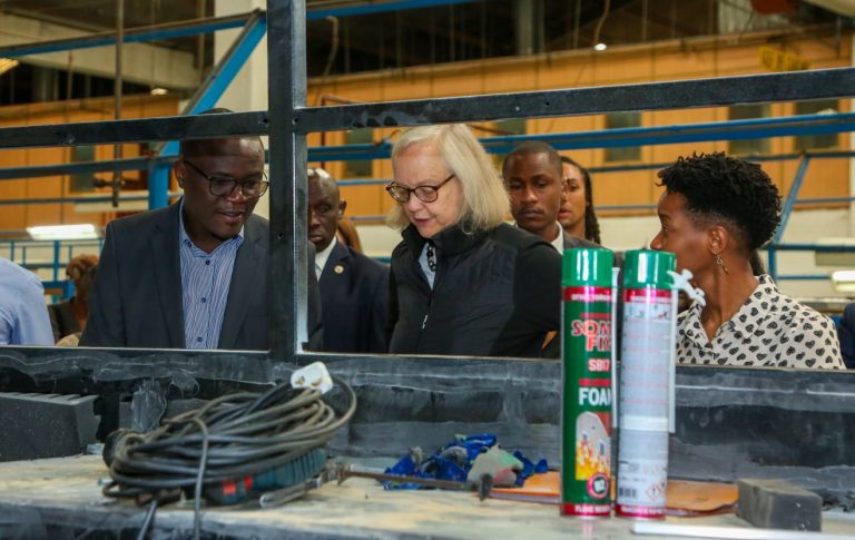 From Left, Moses Abiero, General Manager, Kenya Vehicle Manufacturers, explains the painting process of an electric bus to Meg Whitman, U.S. Ambassador to Kenya as Marian Muthui, Head of Manufacturing - BasiGo Kenya, looks on.