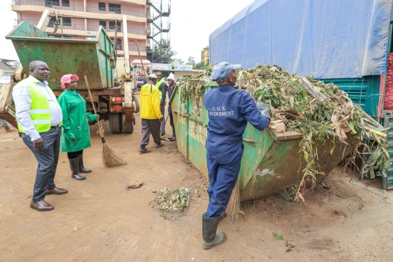 Kirinyaga County CEC for Environment James Mutugi watches as cleaners load waste into one of the skips at Kagio market.