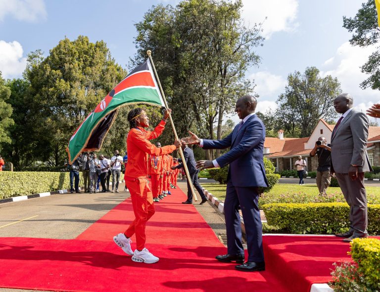 President William Ruto at the Eldoret Sports Club in Uasin Gishu County, receives flag from olympiad captain Faith Kipyegon looking on far right Deputy President Rigathi Gachagua