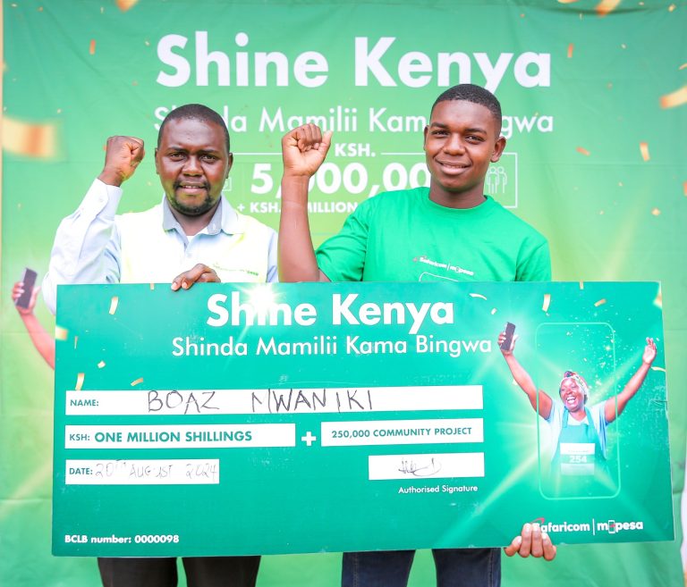 Cosmus Maluki Trade Development Representative Mwingi North at Safaricom(Left) handing a dummy check to Boaz Mwaniki winner of ksh. 1 Million at Shine Kenya Handover award ceremony held at Migwani in Kitui County