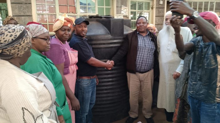Rware MCA Simon Mbogo (in brown jacket) handing over a water storage tank to Nyeri town open air market's chairman Earnest Kuria