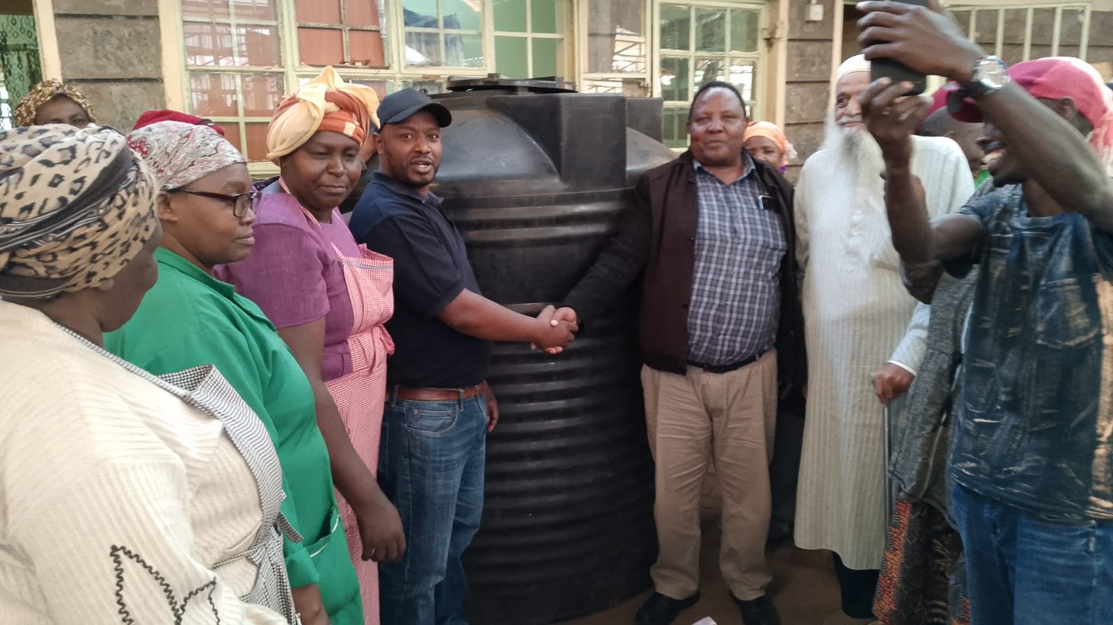 Rware MCA Simon Mbogo (in brown jacket) handing over a water storage tank to Nyeri town open air market's chairman Earnest Kuria