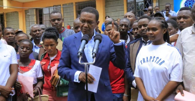 Dr Alfred Mutua briefing journalists in the company of jobseekers