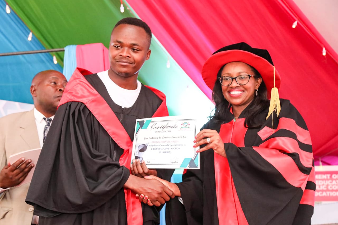 Governor Susan Kihika presenting a certificate to Austin Irungu who graduated with a certificate in Building and Construction - Plumbing Option