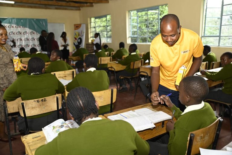 Cliff Onyango, BIC East Africa Sales Representative, distributes pens to eager students at Arap Moi Primary School