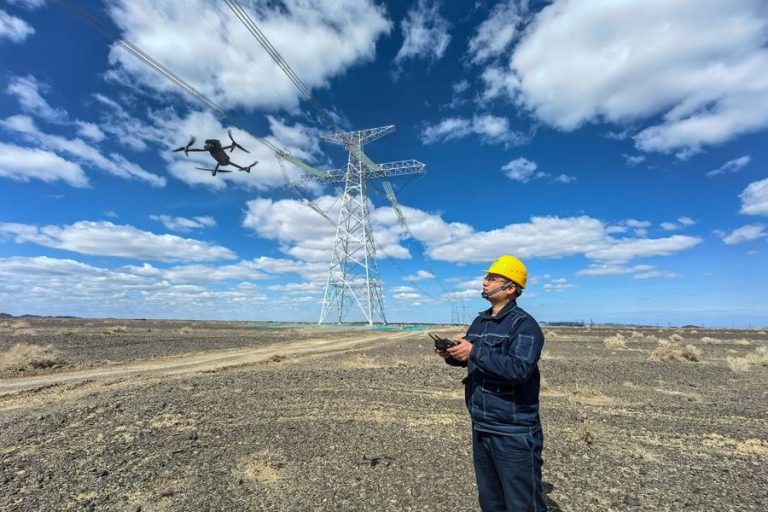 A staff member operates a drone to check cables of the Hami-Chongqing