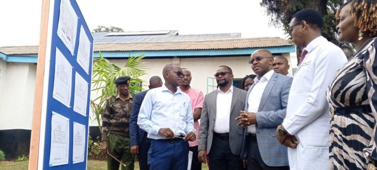 Defence PS Patrick Mariru (in light blue coat) is shown a design of the buildings that will be put up in Meru Teaching and Referral Hospital.