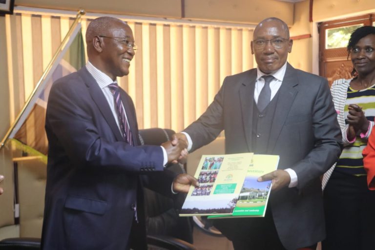 Tharaka Nithi County health CECM Dr Gichuiyia Nthuraku (left) and Karatina University VC Prof Linus Gitonga exchange MoU documents.