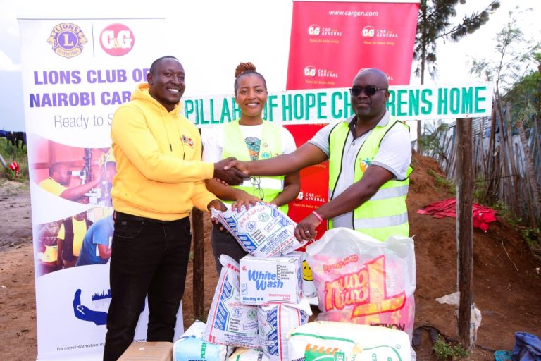 Victor Owuor, the president of the Lions Club of Naitobi Cargen (left) hands over assorted foodstuff to Vitalis Nyambeka (right),