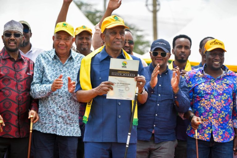 Ali Korane showing the UDA Silver membership certificate as the party officials and supporters look on.