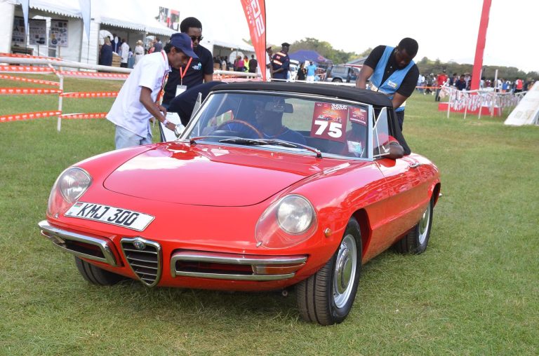 Judges examine the gleaming 1969 Alfa Romeo Spider of Alec Davis at a past event.