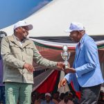 CS Mutahi Kagwe (left) handing over a trophy to Wakulima dairy chairman Muhika Mutahi.