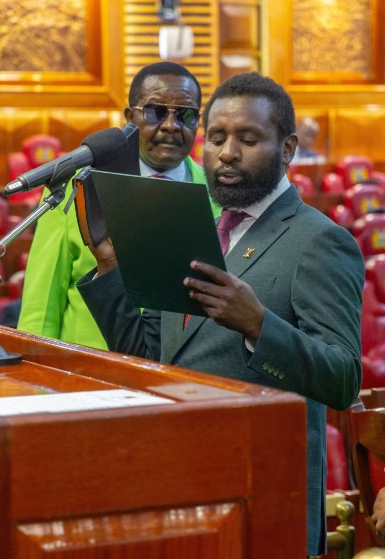Sammy Kamau swearing in as Roysambu MP Kamande Mwafrika looks on.